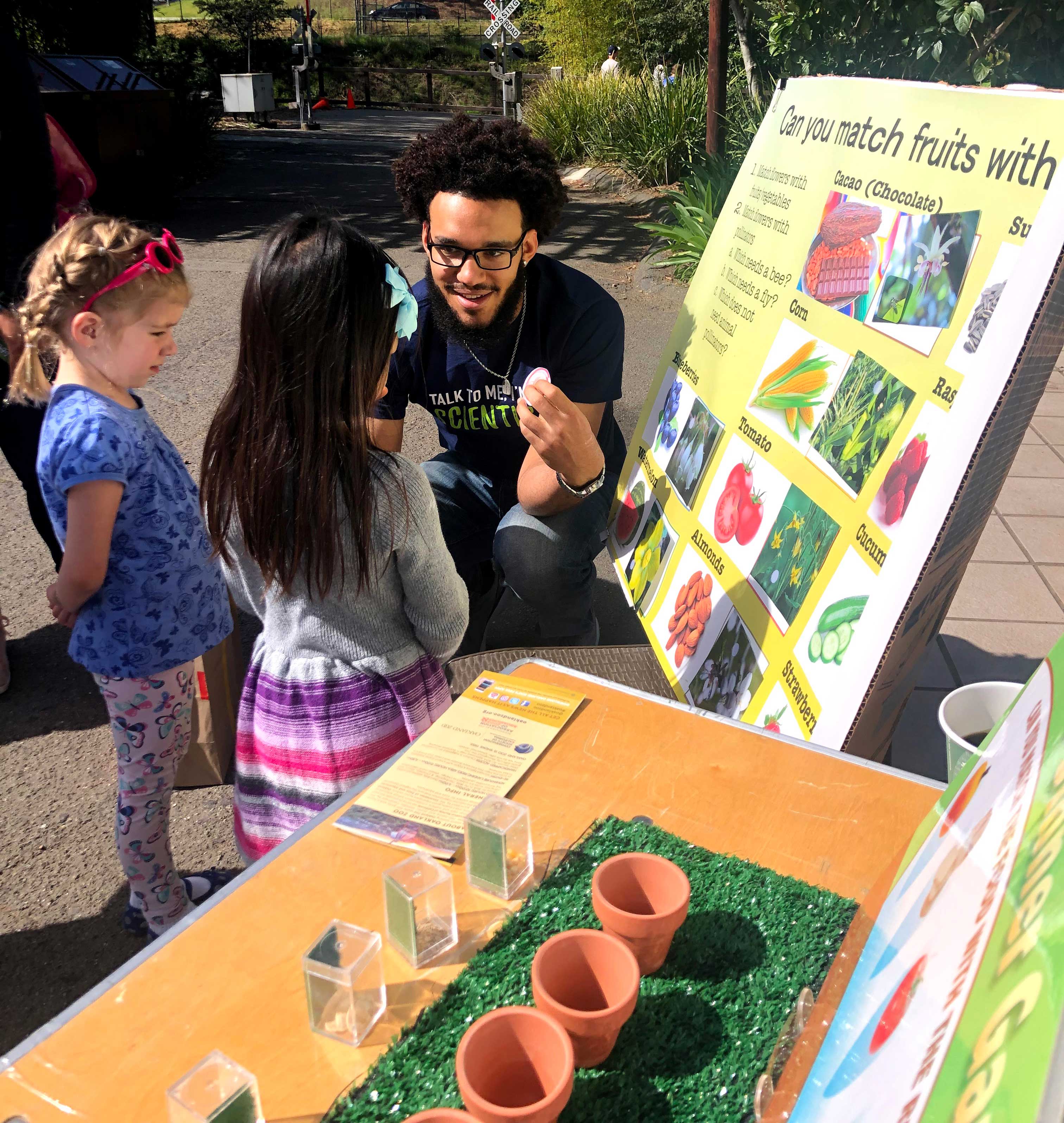 A man teaching young children about fruits in an outdoor setting