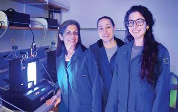 Sabeeha Merchant and other lab members standing in a lab next to a bioreactor.